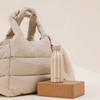 Bouteille isotherme Qwetch Icon Allure Lin 500ml beige rayée posée sur un bloc devant un sac Du Bruit dans la Cuisine