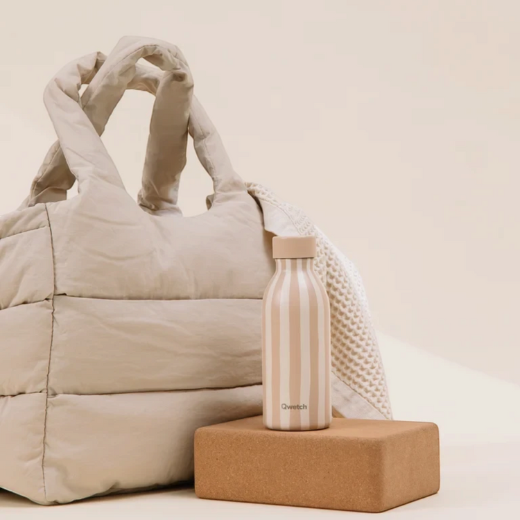 Bouteille isotherme Qwetch Icon Allure Lin 500ml beige rayée posée sur un bloc devant un sac Du Bruit dans la Cuisine