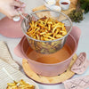 Panier de friture en acier inoxydable Cookut de 28 cm rempli de frites maison au-dessus d'une cocotte rose